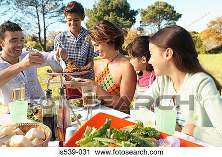 Stock Image - Family eating in garden. Fotosearch