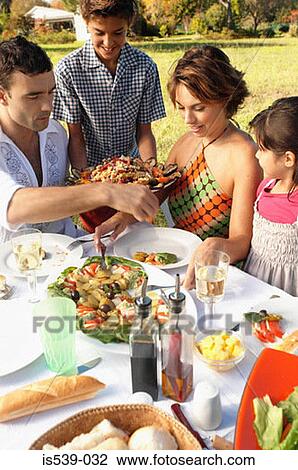 Stock Image - Family eating in garden. Fotosearch