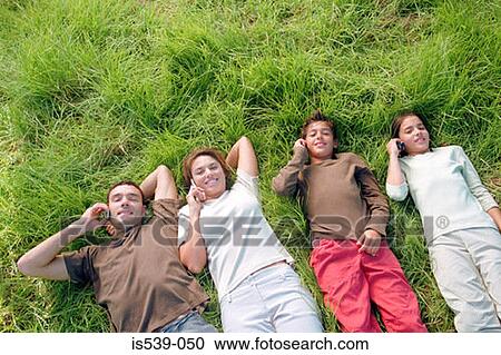 Stock Image - Family using mobile phones in field. Fotosearch