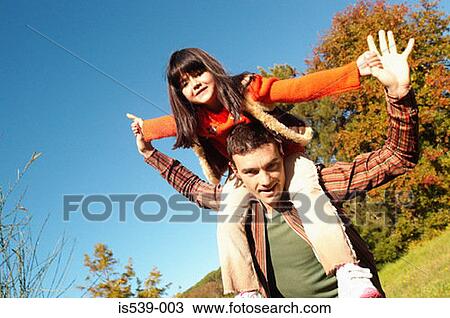 Stock Image - Father shoulder carrying daughter. Fotosearch