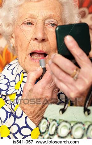 Elderly woman applying lipstick View Large Photo Image Stock Photo - Elderly woman applying lipstick. Fotosearch