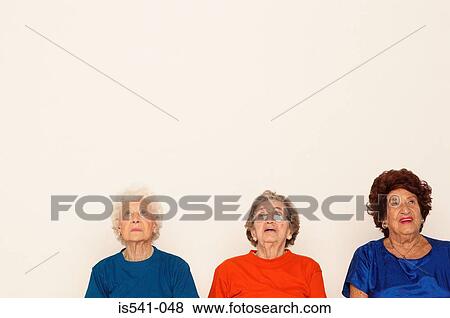 Stock Photo - Three elderly women looking up. Fotosearch