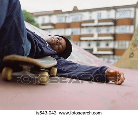 Boy lying on skateboard ramp View Large Photo Image Stock Image - Boy lying on skateboard ramp. Fotosearch