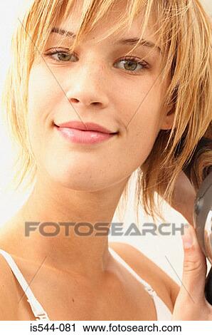 Stock Image - Smiling young woman drying her hair. Fotosearch