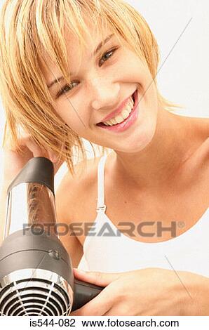 Smiling young woman drying her hair View Large Photo Image Stock Image - Smiling young woman drying her hair. Fotosearch