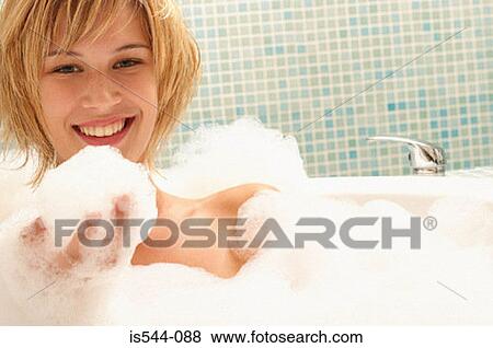 Stock Photo - Smiling young woman in bubble bath. Fotosearch