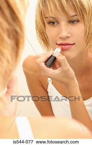 Young woman applying lipstick View Large Photo Image Stock Photo - Young woman applying lipstick. Fotosearch