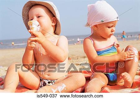 Stock Photo - Toddlers having ice cream on the beach . Fotosearch