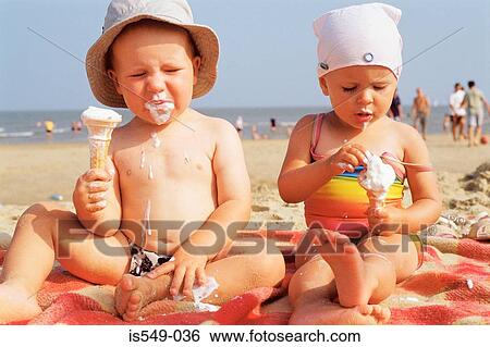 Stock Photograph - Toddlers having ice cream on the beach . Fotosearch