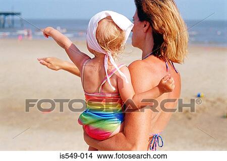 Picture - Woman carrying a toddler on the beach . Fotosearch