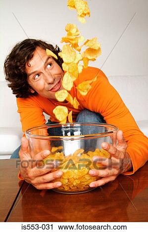 Young man with bowl of crisps View Large Photo Image Stock Image - Young man with bowl of crisps. Fotosearch