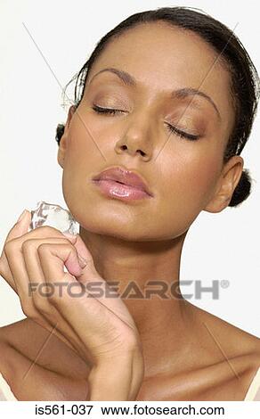 Woman holding ice cube on face View Large Photo Image Stock Photo - Woman holding ice cube on face. Fotosearch