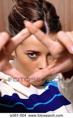 Picture - Woman looking through fingers. Fotosearch
