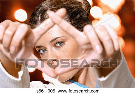 Stock Photography - Woman looking through fingers. Fotosearch