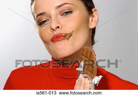 Stock Image - Young woman eating chocolate. Fotosearch