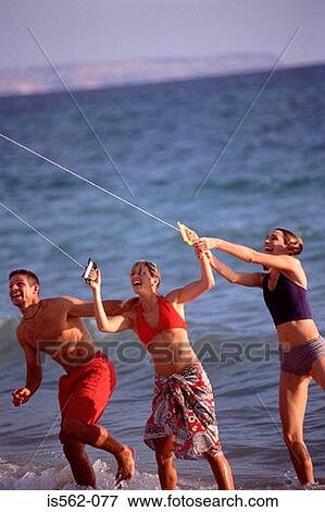 Friends on beach flying kite View Large Photo Image Stock Photo - Friends on beach flying kite. Fotosearch