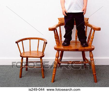 Picture - Boy and little and large chairs. Fotosearch