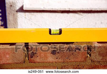 Stock Image - Spirit level on brick wall. Fotosearch