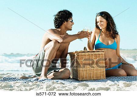 Stock Image - Couple having picnic on beach. Fotosearch