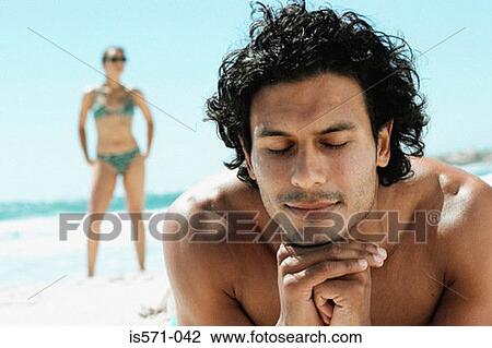 Stock Image - Man sunbathing on beach. Fotosearch