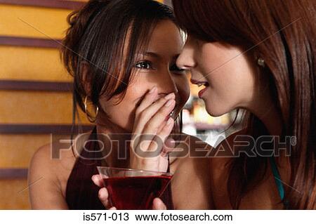 Stock Image - Women whispering in bar. Fotosearch