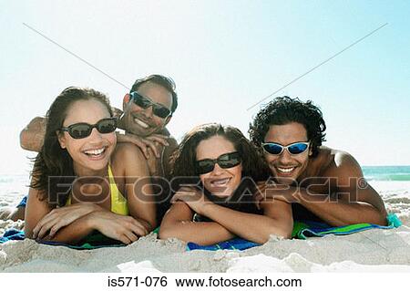 Stock Photograph - Young couples lying on beach. Fotosearch