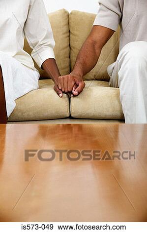Couple holding hands on sofa View Large Photo Image Stock Photo - Couple holding hands on sofa. Fotosearch
