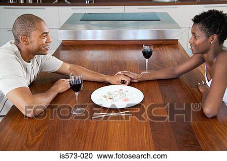 Stock Image - Couple sitting at dining table. Fotosearch