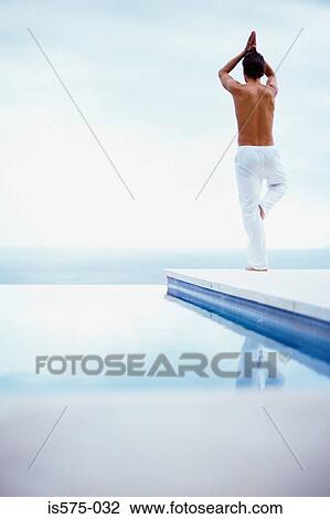 Stock Image - Yoga by the swimming pool. Fotosearch