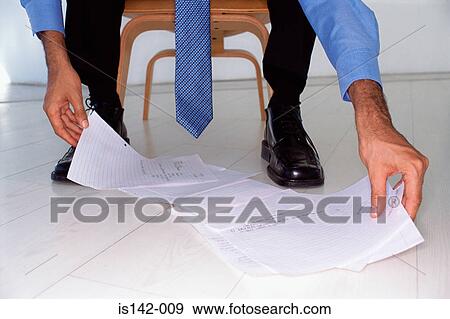Businessman looks at papers View Large Photo Image Stock Photo - Businessman looks at papers. Fotosearch