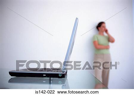 Stock Image - Laptop and female on the phone. Fotosearch