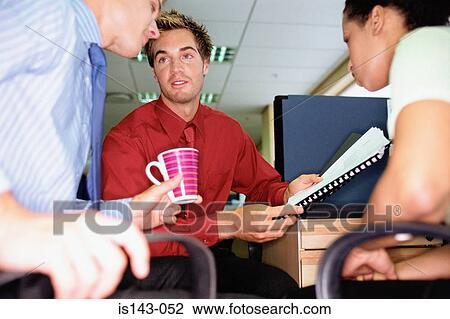 Stock Image - Colleagues discuss paperwork. Fotosearch