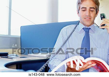 Stock Photo - Man at desk on the phone. Fotosearch