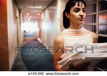 Stock Image - Woman carrying stack of paper. Fotosearch