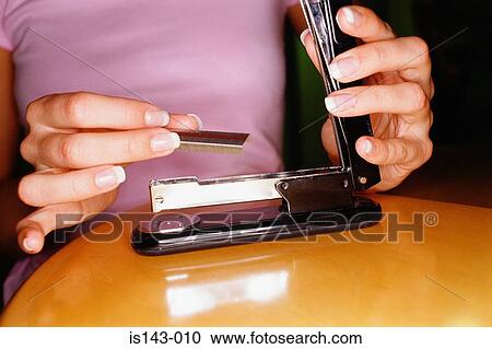 Stock Image - Woman refilling stapler. Fotosearch