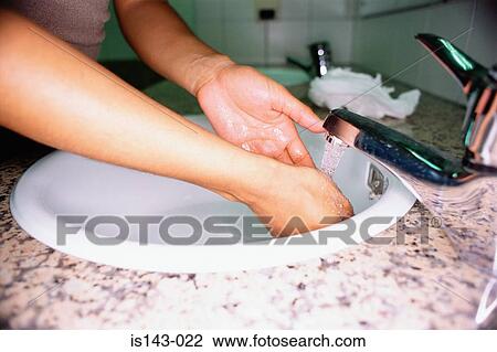 Stock Image - Woman washing hands in basin. Fotosearch