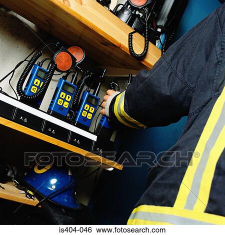 Stock Photograph - Fireman picking up radio. Fotosearch