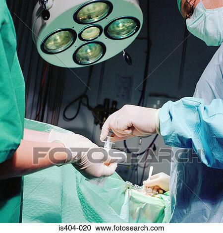 Stock Image - Nurse handing sterile tools. Fotosearch