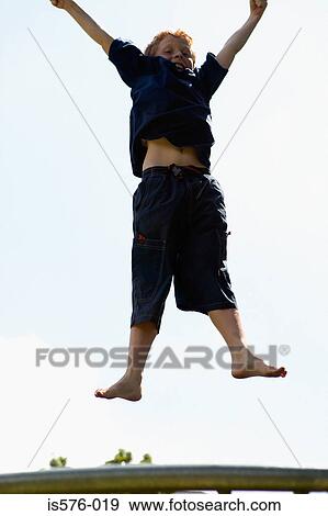 Stock Photo - Young boy on trampoline. Fotosearch