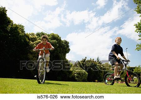 Young boys cycling in park View Large Photo Image Stock Photograph - Young boys cycling in park. Fotosearch