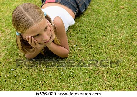 Stock Image - Young girl lying on the grass. Fotosearch