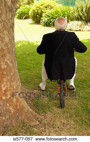 Older man in garden on bicycle View Large Photo Image Stock Photo - Older man in garden on bicycle. Fotosearch