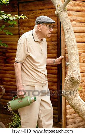 Stock Image - Older man outdoors with flask. Fotosearch
