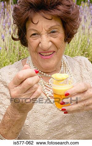 Stock Image - Older woman enjoying dessert. Fotosearch