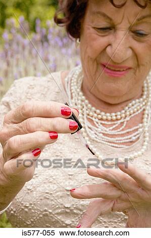 Stock Photography - Older woman painting garden. Fotosearch