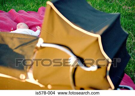 Picture - Classic pram with baby chilling out on pink blanket. Fotosearch