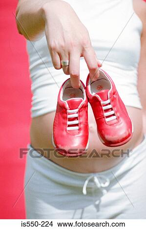 Picture - Mother-to-be holding child's trainers . Fotosearch