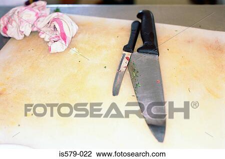 Stock Image - Used knives on chopping board. Fotosearch