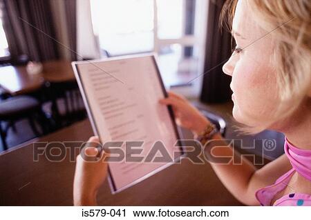 Stock Image - Young woman reads the menu. Fotosearch