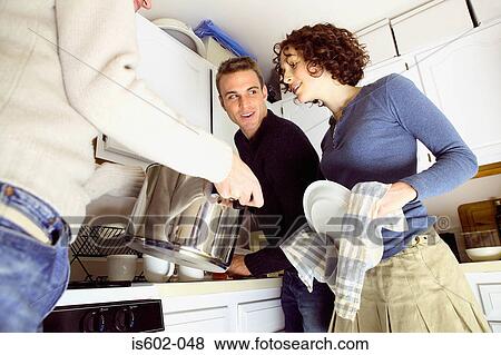 Stock Photo - Friends standing in kitchen. Fotosearch